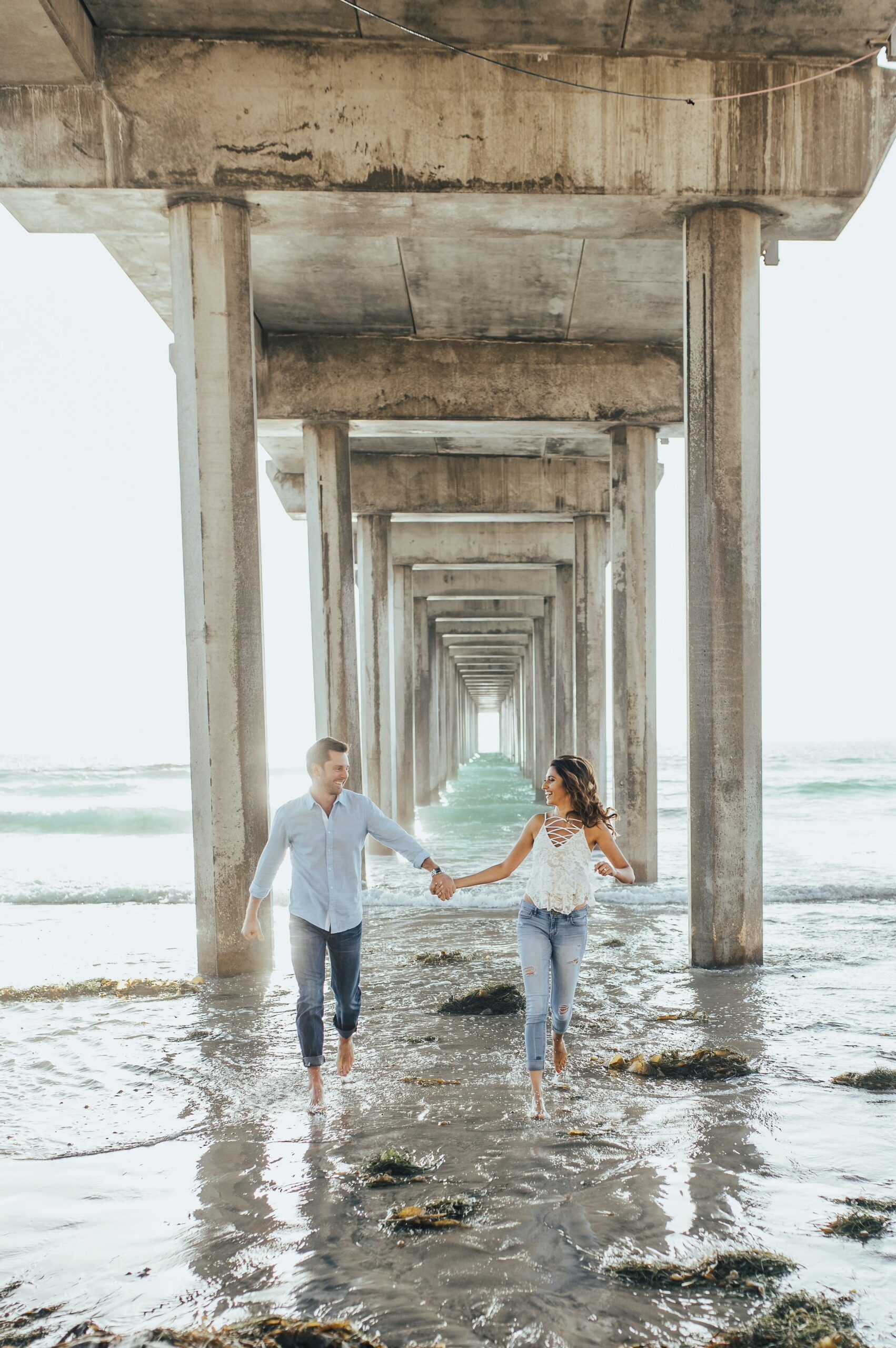 Pam and Matt walking through the surf under the pier